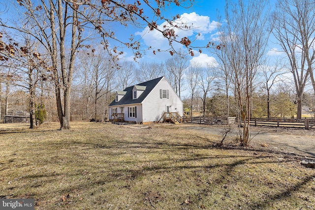 view of side of home with dirt driveway, a yard, and fence