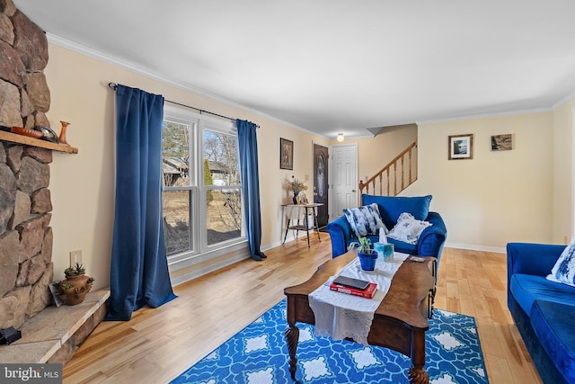 living area featuring stairway, baseboards, wood finished floors, and crown molding