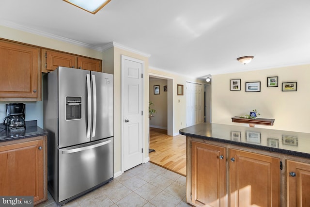 kitchen featuring crown molding, light tile patterned floors, brown cabinetry, and stainless steel refrigerator with ice dispenser