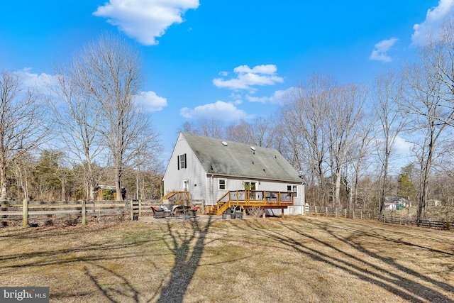 rear view of house with a shingled roof, a wooden deck, a yard, and fence