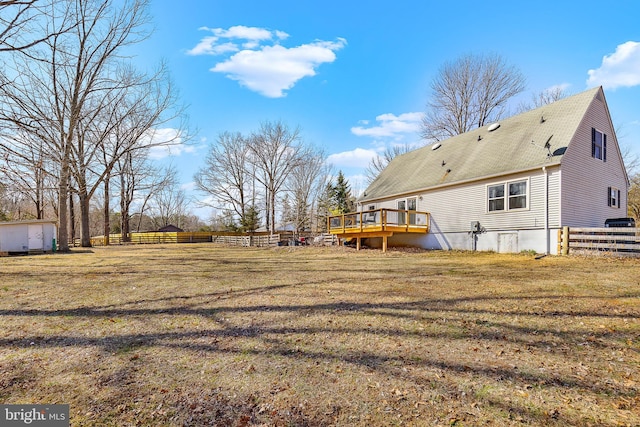 exterior space with a yard, an outbuilding, a deck, and fence