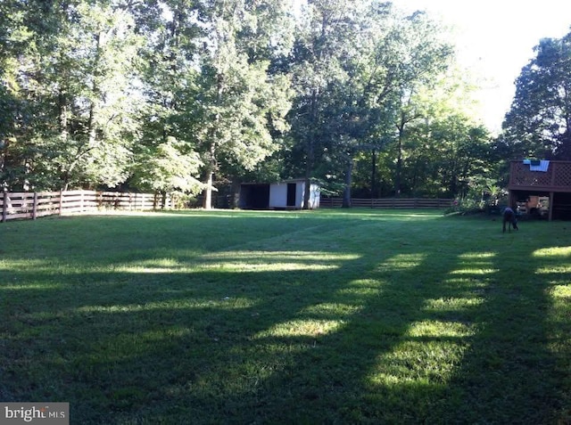 view of yard with a storage shed, an outdoor structure, and fence