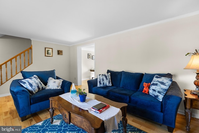 living area featuring stairs, wood finished floors, baseboards, and ornamental molding