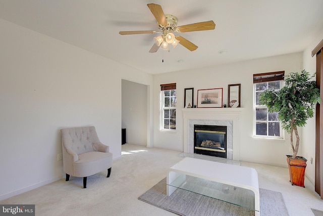 living room featuring a premium fireplace, baseboards, carpet, and ceiling fan