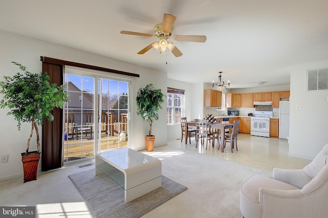 living area featuring visible vents, light carpet, and ceiling fan with notable chandelier