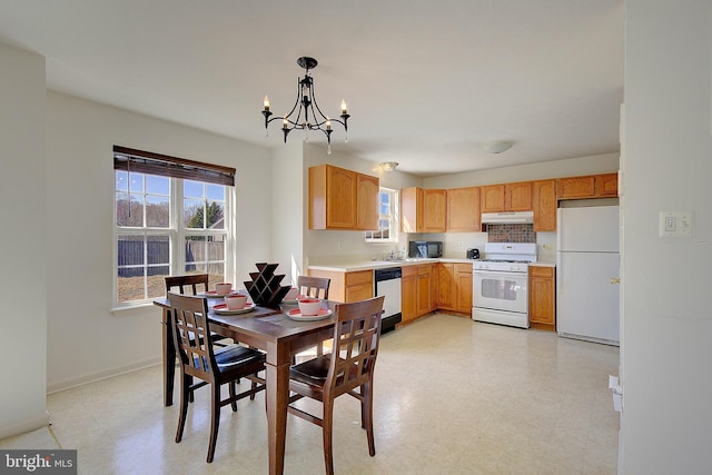 dining area featuring a healthy amount of sunlight, light floors, baseboards, and a chandelier