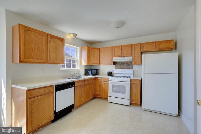 kitchen featuring under cabinet range hood, a sink, white appliances, light countertops, and light floors