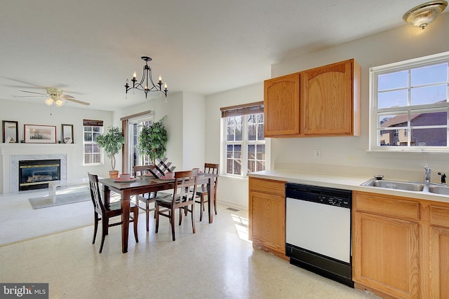 kitchen with a sink, a high end fireplace, white dishwasher, and light countertops