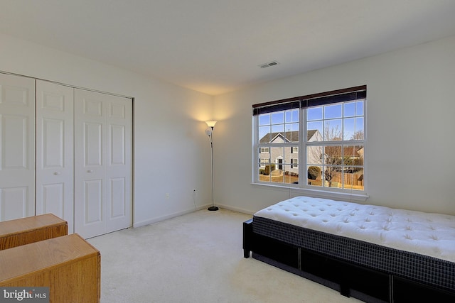 bedroom with carpet, visible vents, a closet, and baseboards