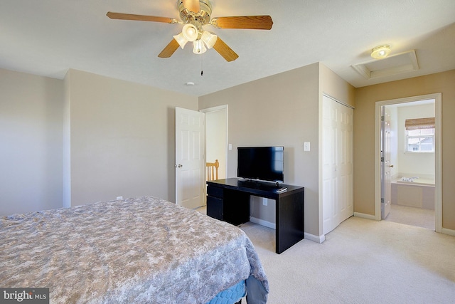 bedroom with a ceiling fan, baseboards, attic access, ensuite bathroom, and light colored carpet