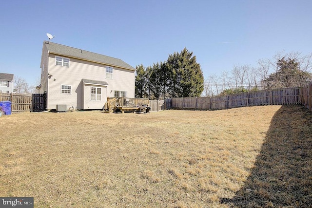 rear view of house with a fenced backyard, a deck, central AC unit, and a yard