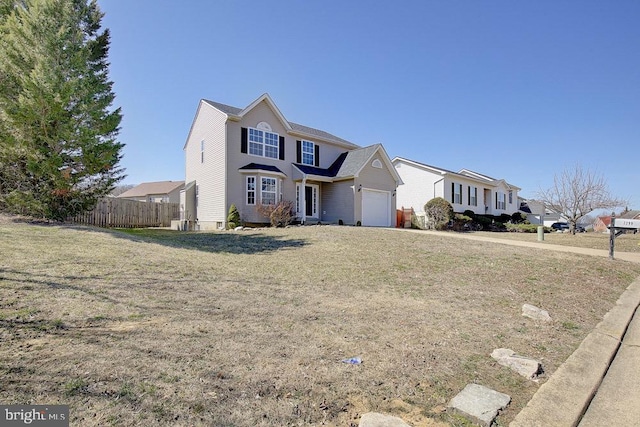 traditional-style home featuring an attached garage, a front yard, and fence