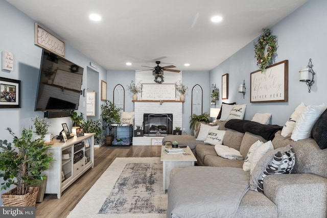 living room with a fireplace, recessed lighting, wood finished floors, and a ceiling fan