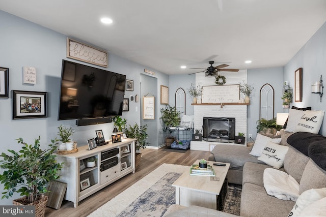 living room featuring a fireplace, recessed lighting, wood finished floors, and a ceiling fan