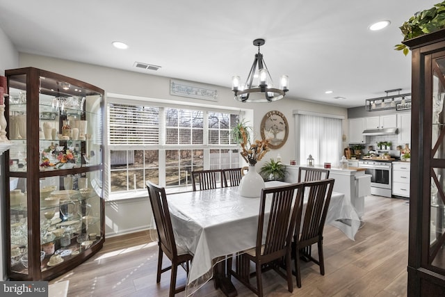 dining room with an inviting chandelier, recessed lighting, light wood-style floors, and visible vents