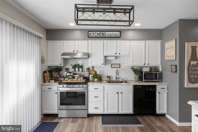 kitchen featuring under cabinet range hood, stainless steel appliances, wood finished floors, and a sink