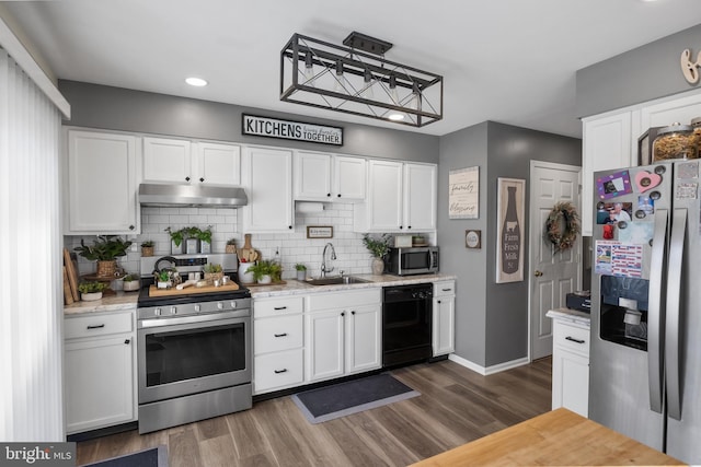 kitchen with under cabinet range hood, white cabinetry, stainless steel appliances, and a sink