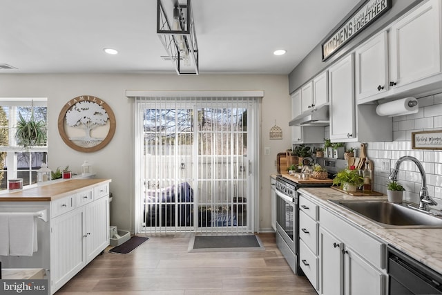 kitchen with under cabinet range hood, light countertops, dishwashing machine, stainless steel electric range, and a sink