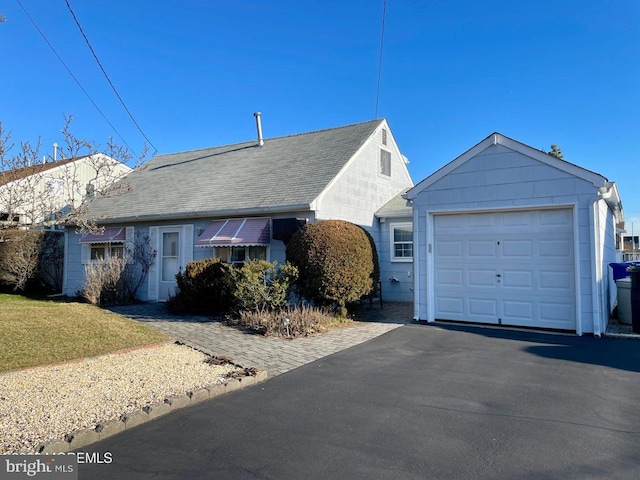 ranch-style home with an outbuilding, driveway, a shingled roof, and a garage