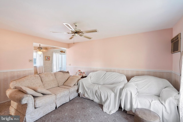 living room with a wainscoted wall, an AC wall unit, and a ceiling fan