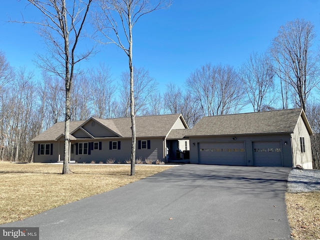 ranch-style home featuring an attached garage, driveway, and roof with shingles