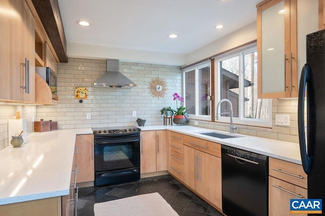 kitchen featuring granite finish floor, recessed lighting, a sink, black appliances, and wall chimney exhaust hood