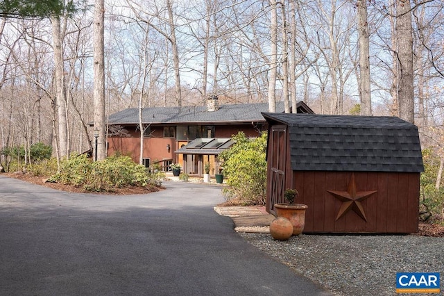 view of front of property with an outbuilding, a storage unit, and a shingled roof