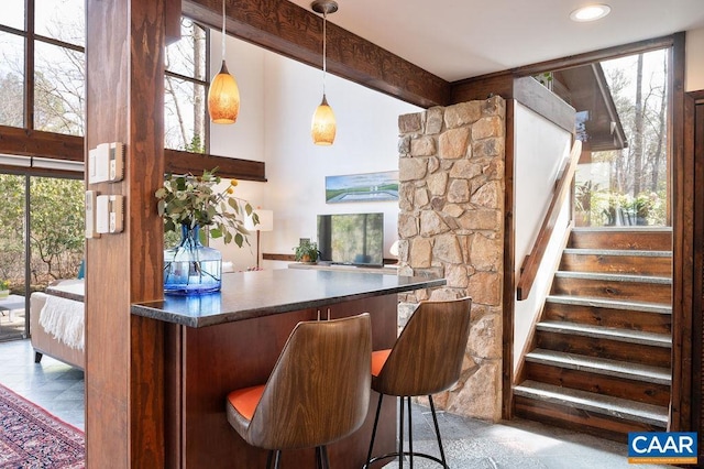 bar with beam ceiling, stairway, pendant lighting, and a bar