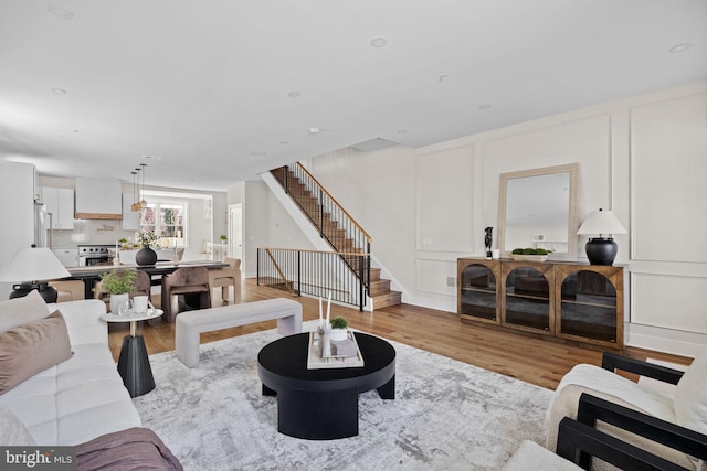 living area featuring a decorative wall, stairway, and wood finished floors