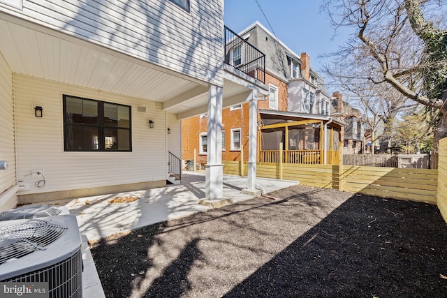 exterior space with cooling unit, fence, and a sunroom