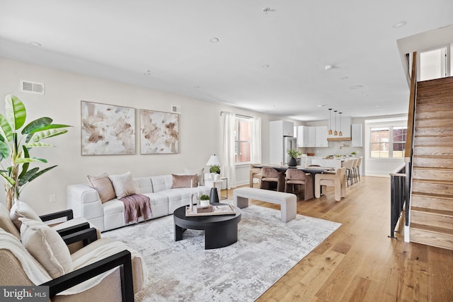 living room with recessed lighting, stairway, light wood-style flooring, and visible vents