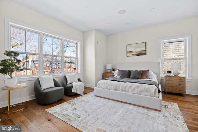 bedroom featuring multiple windows, baseboards, and wood finished floors