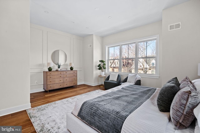 bedroom featuring wood finished floors, visible vents, and baseboards