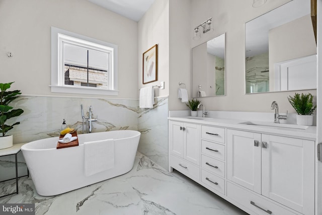 full bathroom featuring double vanity, marble finish floor, a freestanding bath, and a sink