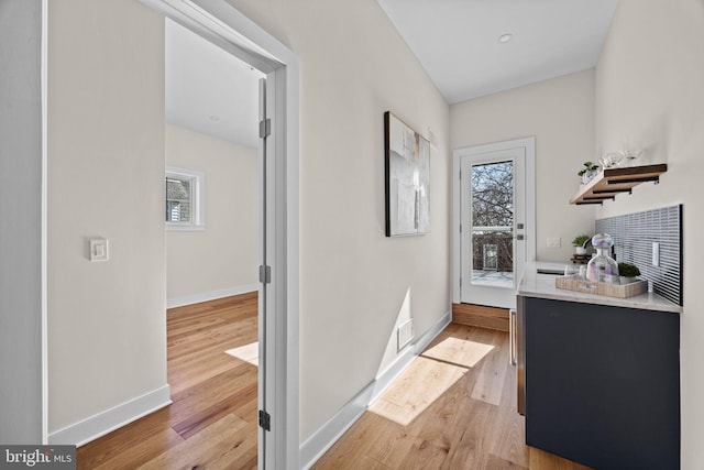 corridor with light wood finished floors and baseboards