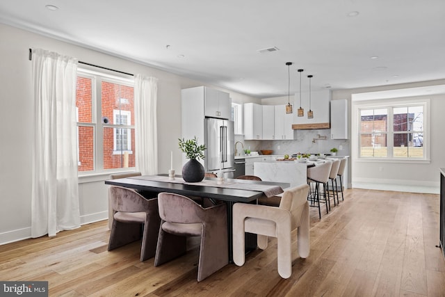 dining space with visible vents, baseboards, and light wood finished floors