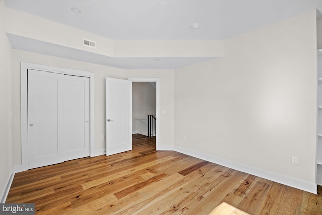 unfurnished bedroom with light wood-type flooring, visible vents, baseboards, and a closet