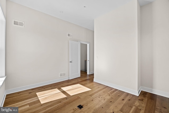 empty room featuring visible vents, baseboards, and wood finished floors