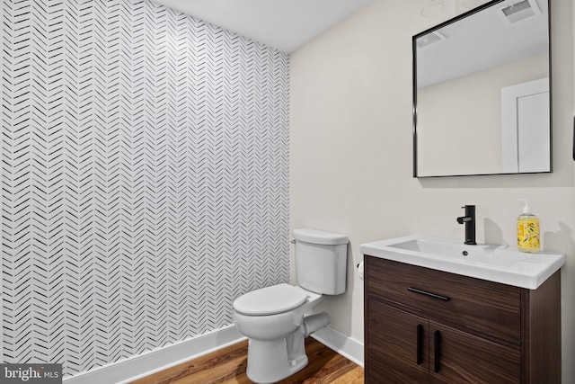 bathroom with visible vents, baseboards, toilet, wood finished floors, and vanity