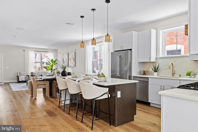 kitchen with a sink, white cabinets, visible vents, and stainless steel appliances