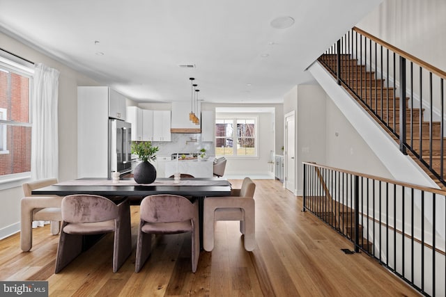 dining space featuring stairs, visible vents, light wood-type flooring, and baseboards