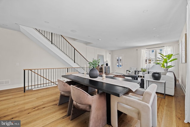 dining room featuring visible vents, baseboards, light wood-style floors, and stairs