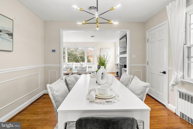 dining area with visible vents, radiator, light wood-type flooring, and an inviting chandelier