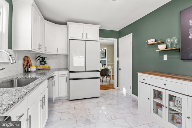 kitchen with white refrigerator, marble finish floor, white cabinets, and a sink