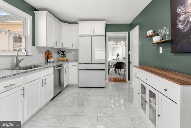 kitchen with stainless steel dishwasher, marble finish floor, and a sink