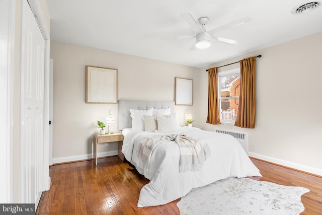 bedroom featuring radiator heating unit, wood finished floors, visible vents, and baseboards