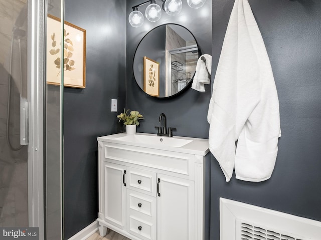 bathroom featuring a shower with door and vanity