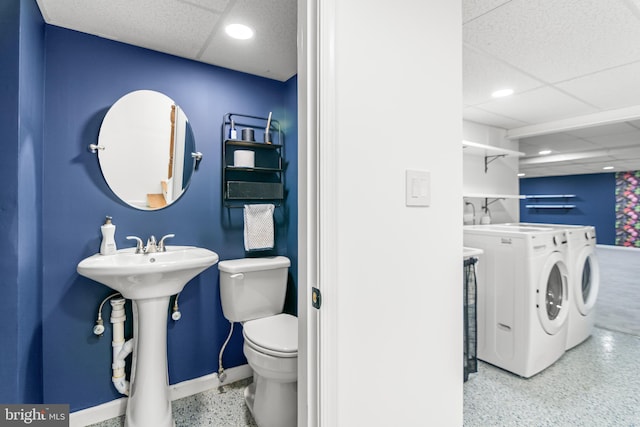 bathroom with baseboards, speckled floor, washing machine and clothes dryer, a drop ceiling, and toilet