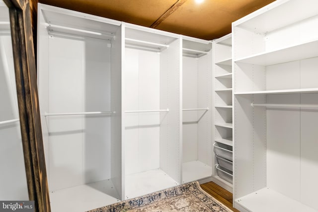 walk in closet with wood finished floors