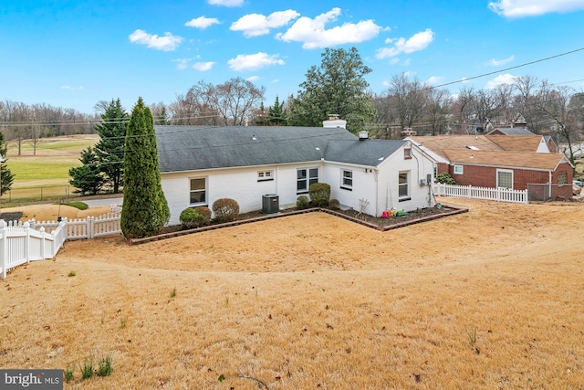 rear view of house with brick siding, central AC, and a fenced backyard